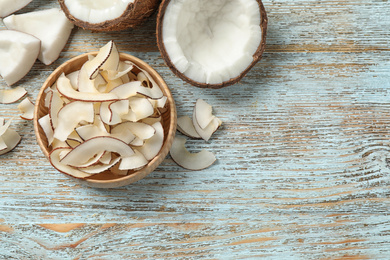 Flat lay composition with tasty coconut chips on light blue wooden table. Space for text