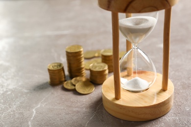 Photo of Hourglass and coins on table. Time management