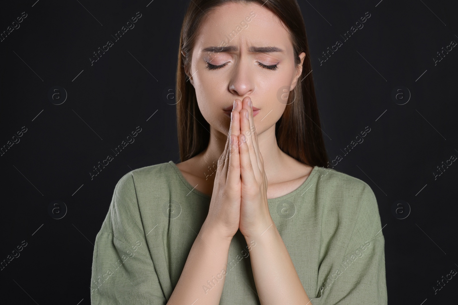 Photo of Woman with clasped hands praying on black background