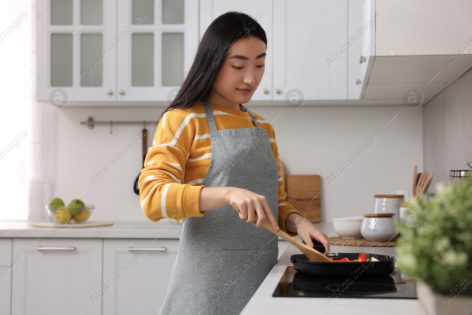 Photo of Beautiful woman cooking vegetable dish in kitchen. Space for text