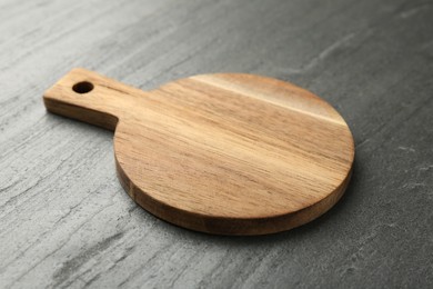 Photo of One wooden cutting board on dark grey table