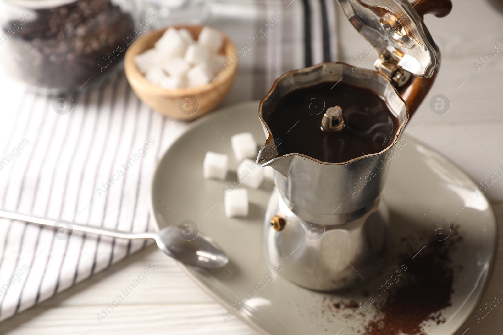 Photo of Brewed coffee in moka pot on white wooden table. Space for text