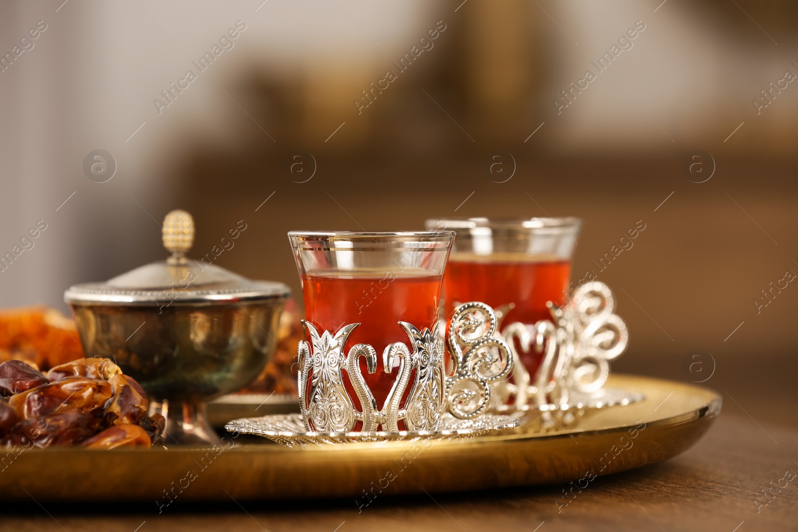 Photo of Glasses with tasty Turkish tea and oriental sweets on wooden table indoors, space for text