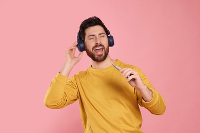 Photo of Emotional man listening music with headphones on pink background