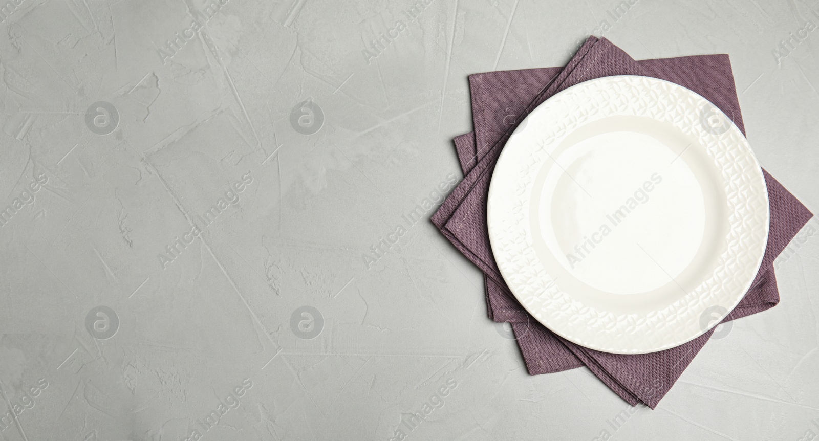 Photo of Empty plate and napkins on grey table, top view. Space for text