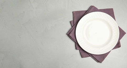 Photo of Empty plate and napkins on grey table, top view. Space for text