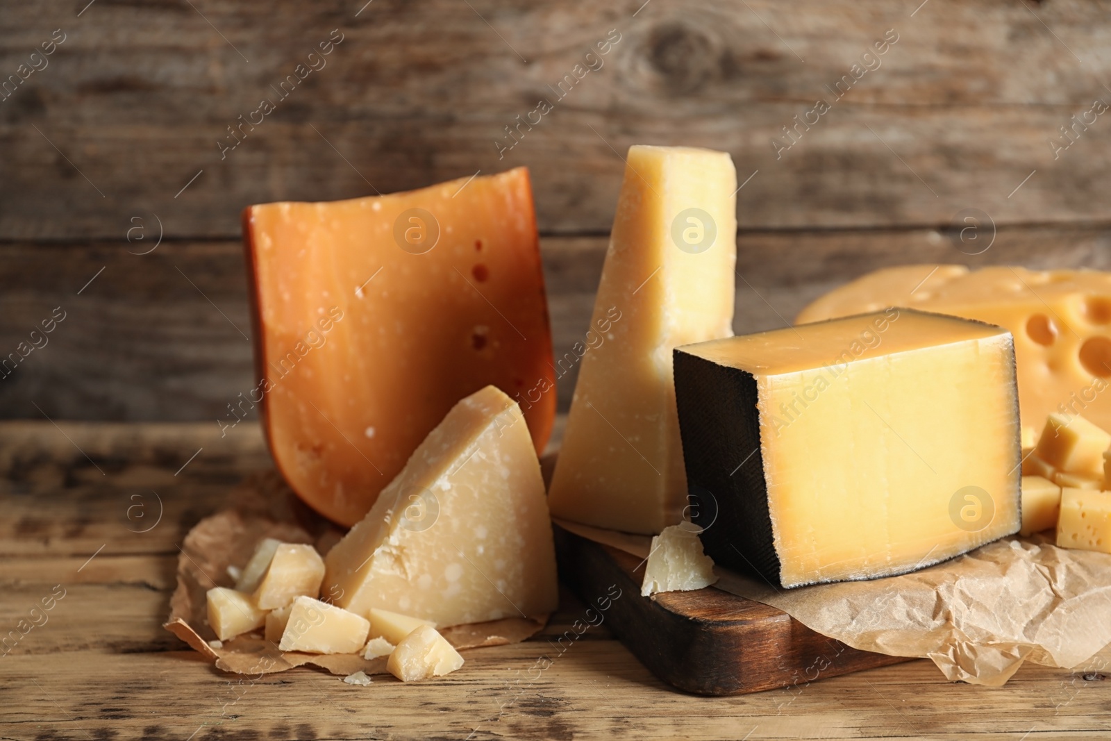 Photo of Different types of delicious cheese on table against wooden background