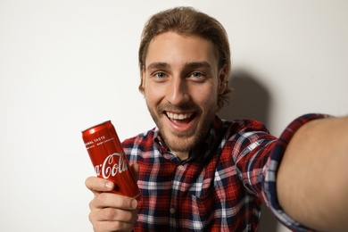 Photo of MYKOLAIV, UKRAINE - NOVEMBER 28, 2018: Young man taking selfie with Coca-Cola can on white background