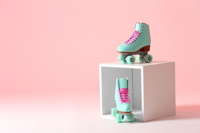 Photo of Pair of vintage roller skates and storage cube on color background. Space for text