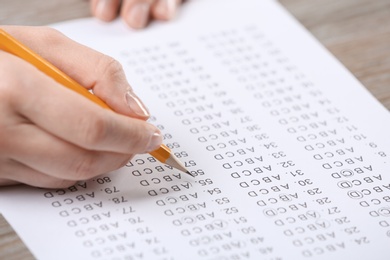 Student filling answer sheet at table, closeup