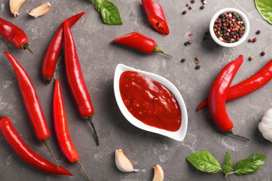 Photo of Flat lay composition with gravy boat of hot chili sauce and different spices on gray background