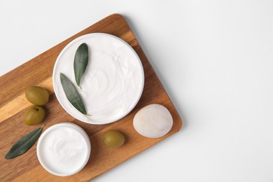 Jars of cream with olives and stone on white background, top view. Space for text