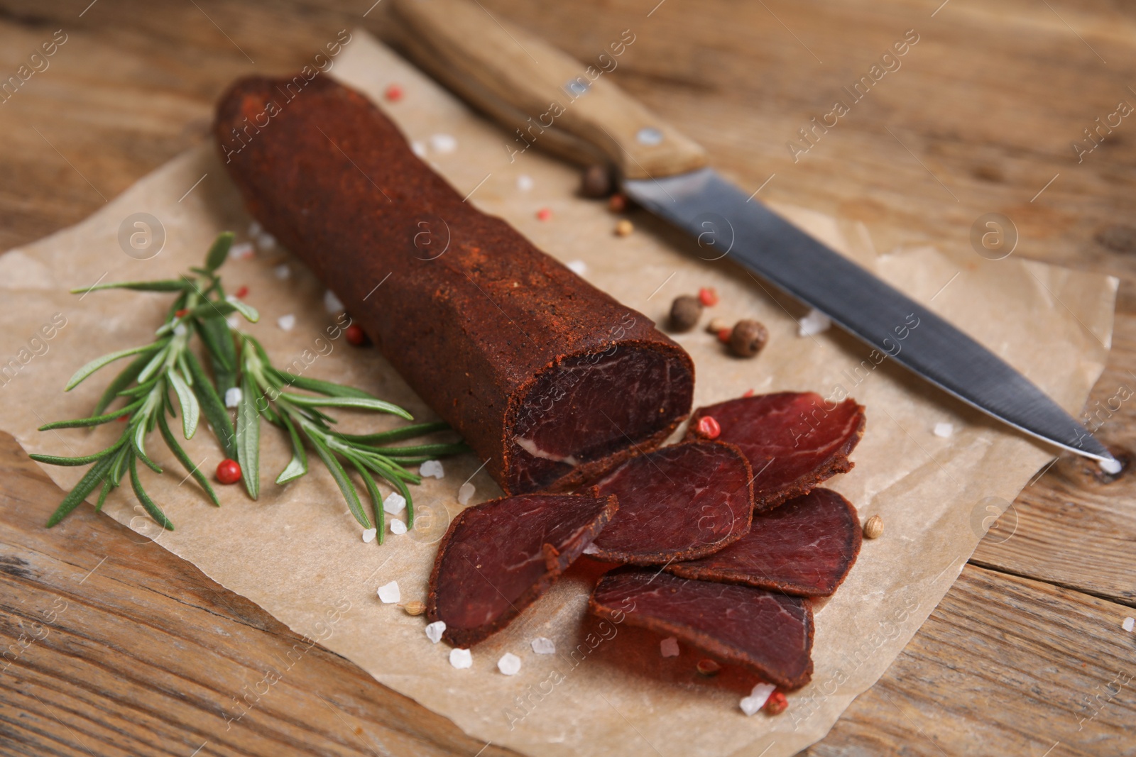 Photo of Delicious dry-cured beef basturma and knife on wooden table, closeup