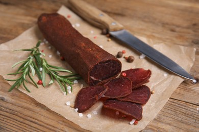 Photo of Delicious dry-cured beef basturma and knife on wooden table, closeup