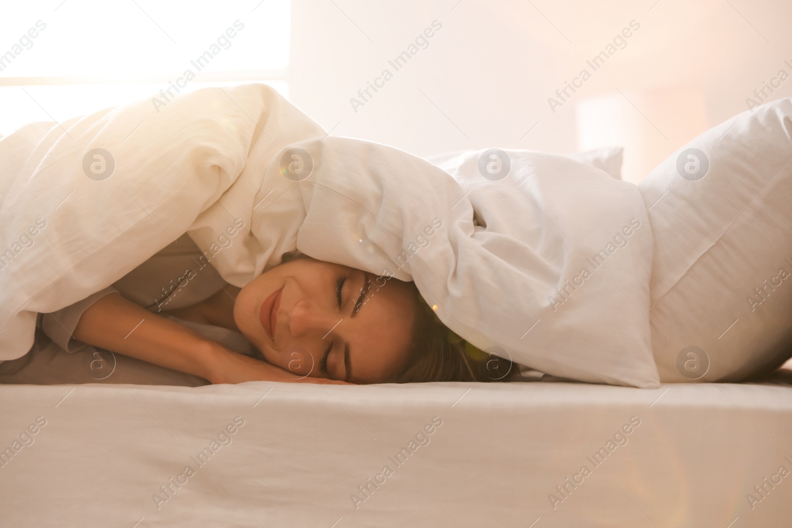 Photo of Woman under warm white blanket sleeping in bed indoors