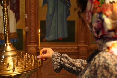 Photo of Mature woman putting candle on stand in church, closeup