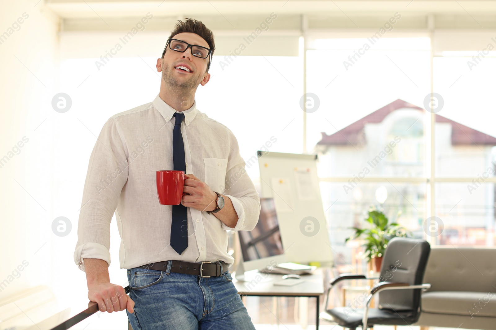 Photo of Young businessman with cup of drink relaxing in office during break