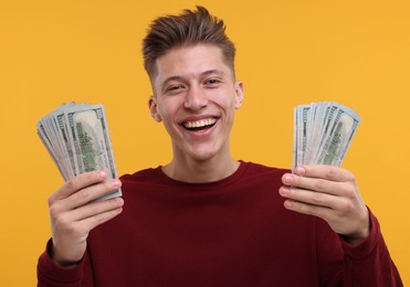 Photo of Happy man with dollar banknotes on yellow background