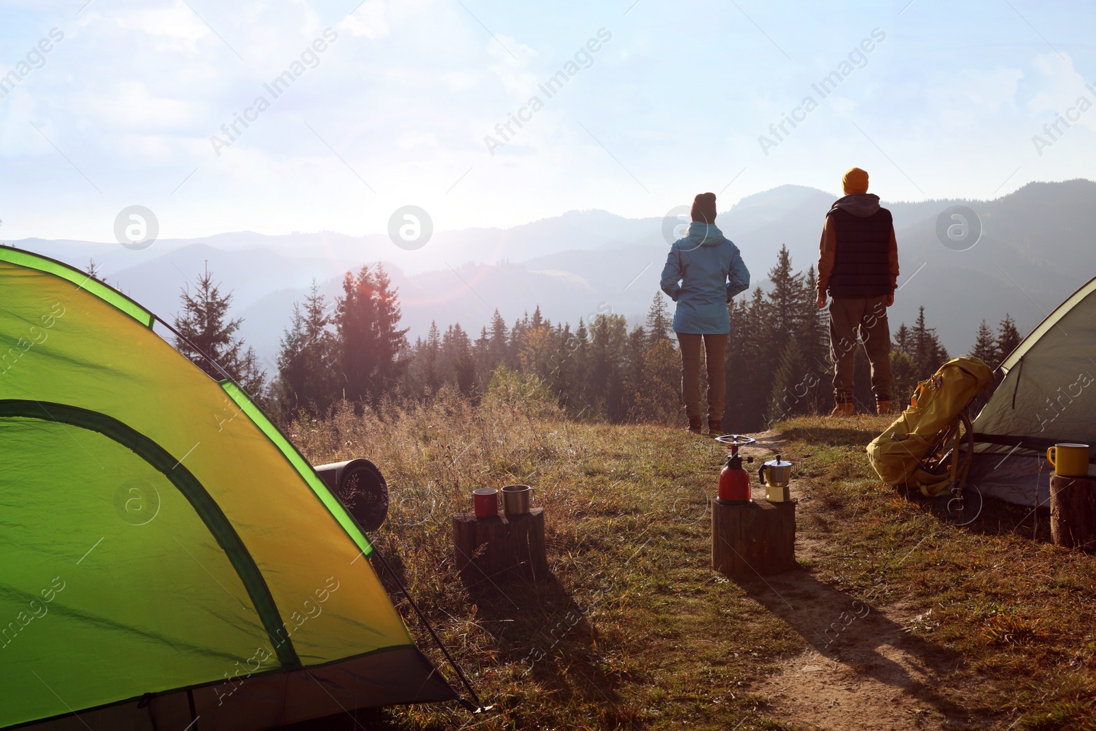 Photo of Couple enjoying beautiful mountain landscape near camping tents, back view