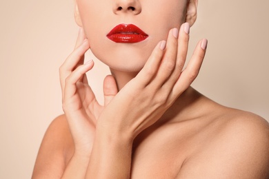 Beautiful young woman with red glossy lips on color background, closeup