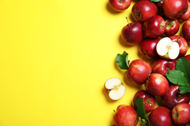 Photo of Tasty red apples on yellow background, flat lay. Space for text
