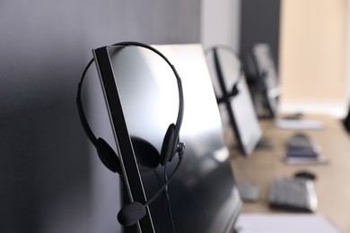 Photo of Modern computer with headset in office. Hotline service