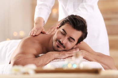 Photo of Handsome young man receiving back massage in spa salon