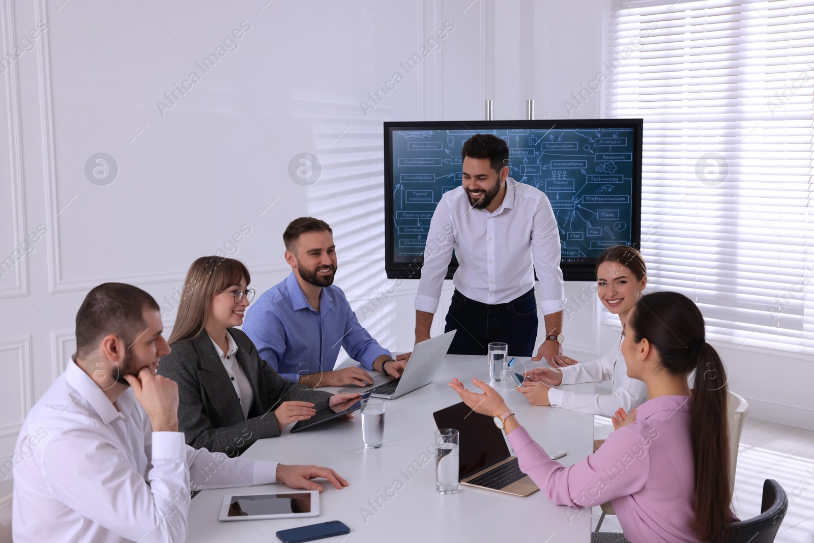 Photo of Business trainer near interactive board in meeting room during presentation