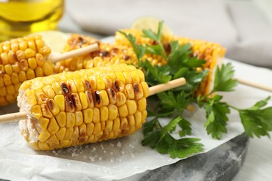 Photo of Tasty grilled corn on table, closeup view