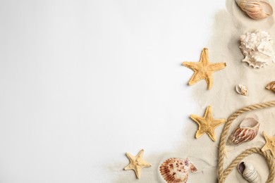 Beautiful sea stars, shells, rope and sand on white background, flat lay. Space for text