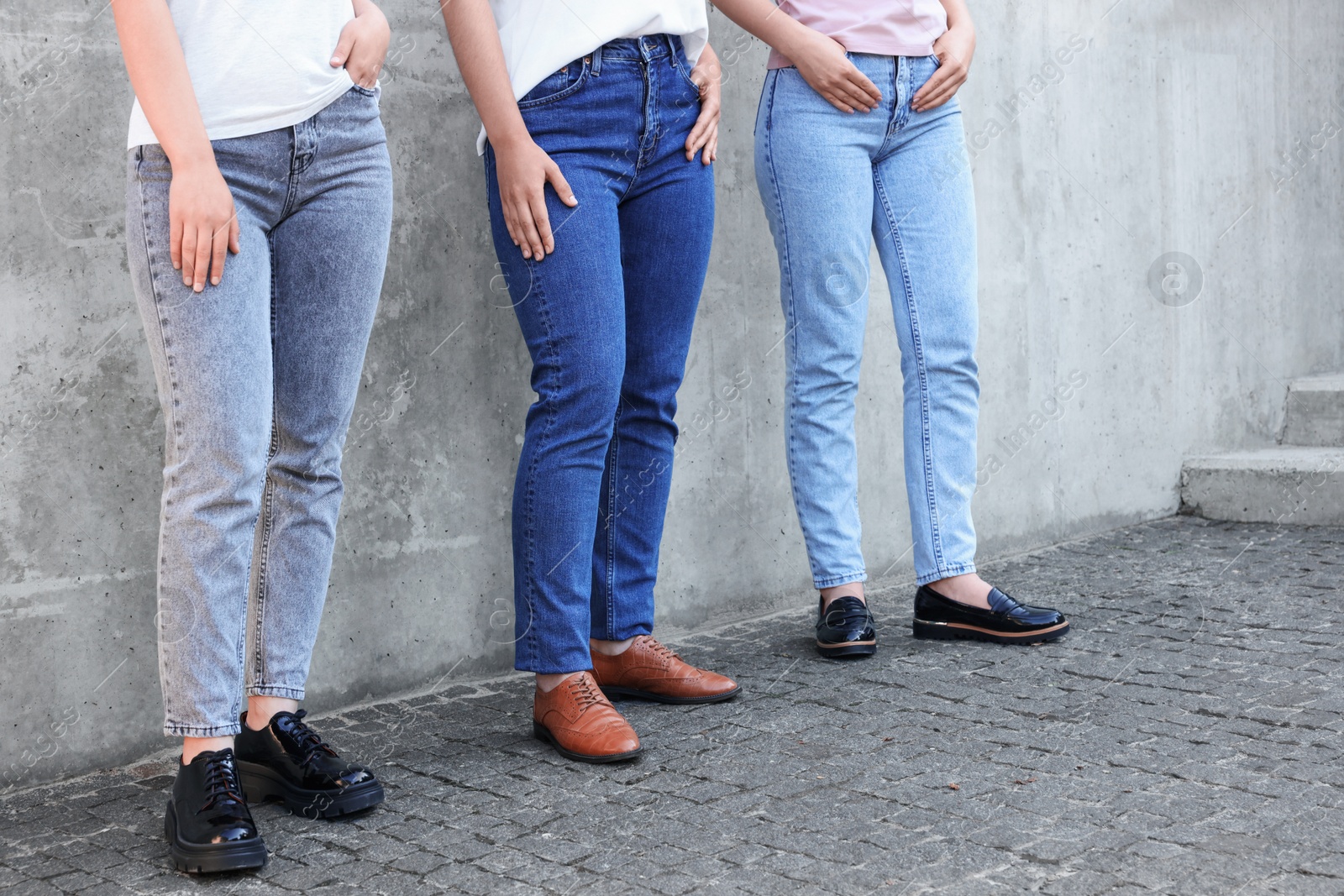 Photo of Women in stylish jeans near grey wall outdoors, closeup