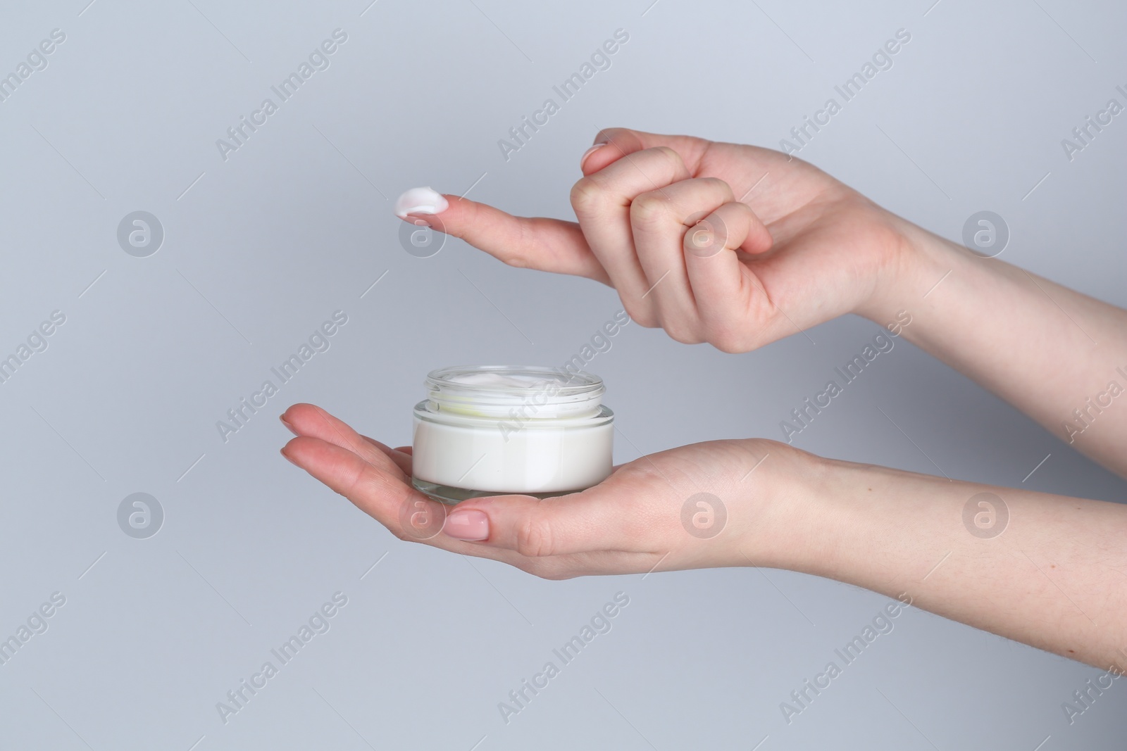 Photo of Woman with jar of cream on grey background, closeup