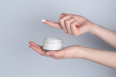 Woman with jar of cream on grey background, closeup