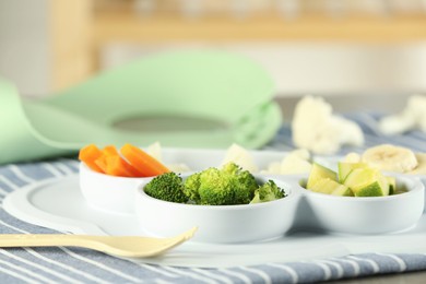 Baby food. Section plate with different vegetables and bananas served on grey textured table, closeup