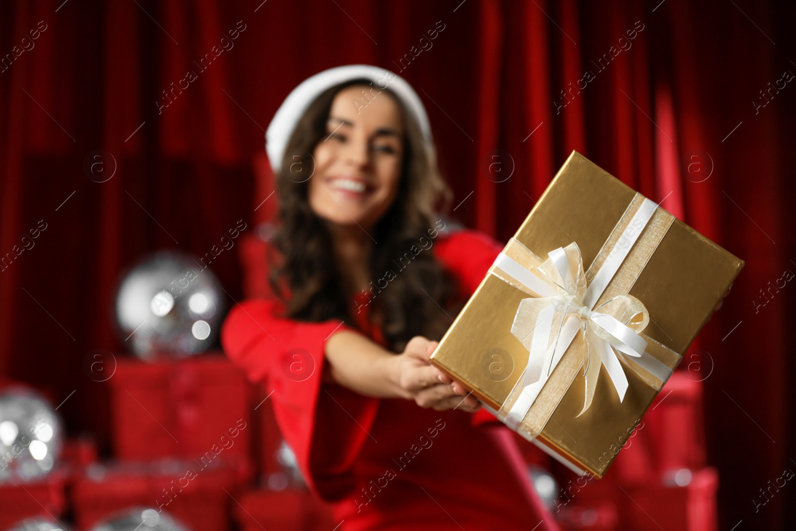 Photo of Beautiful woman with Christmas gift indoors, focus on hands