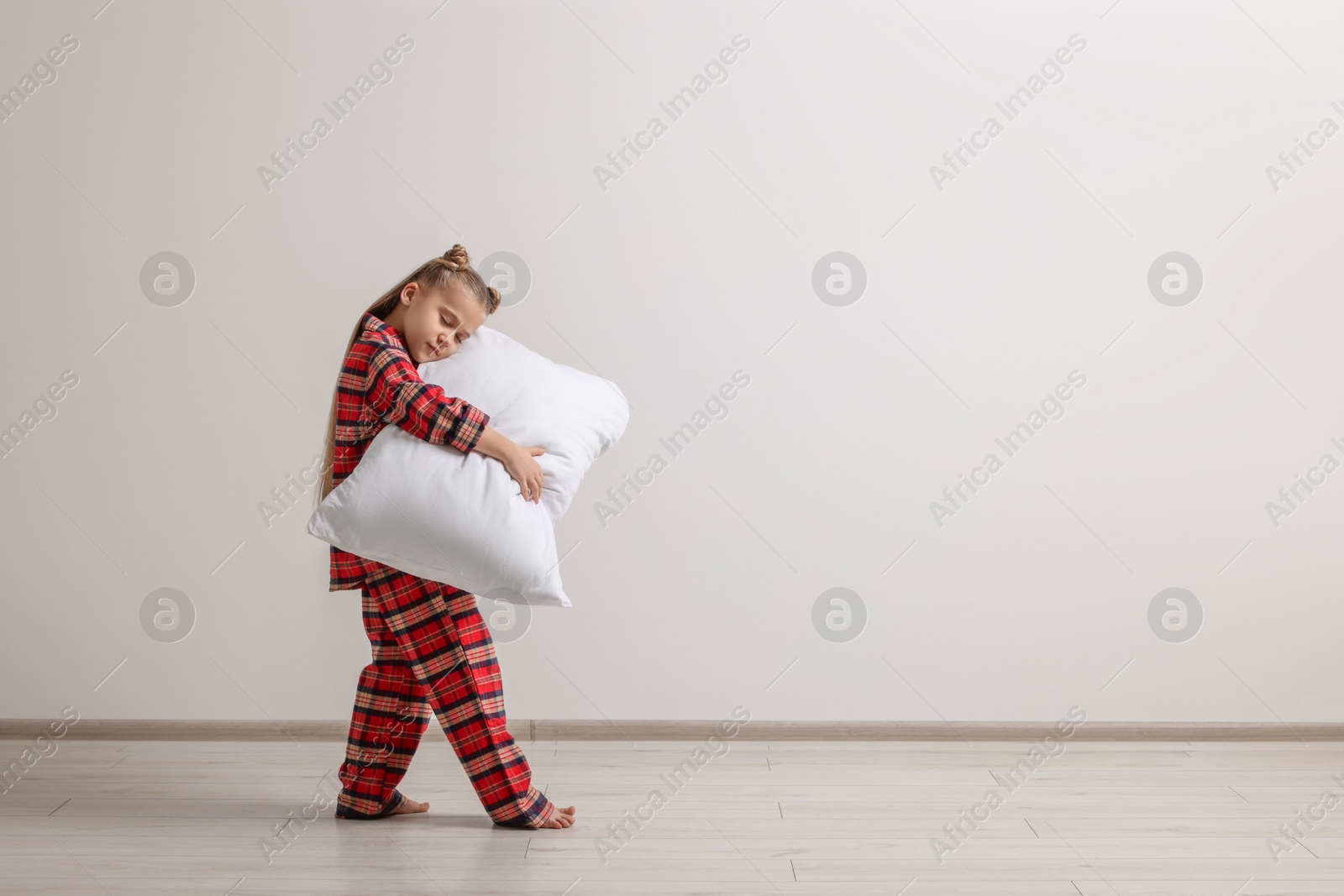 Photo of Girl in pajamas with pillow sleepwalking indoors, space for text