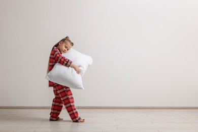 Photo of Girl in pajamas with pillow sleepwalking indoors, space for text