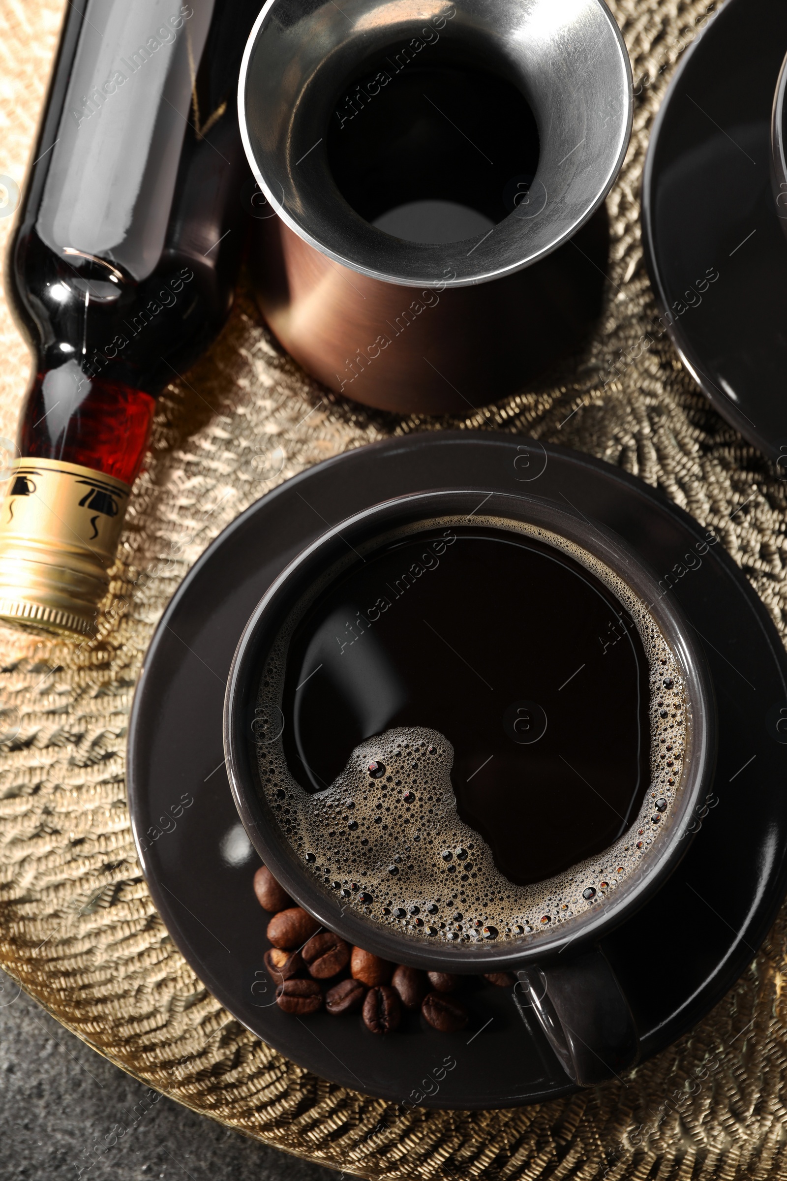 Photo of Bottle of delicious syrup, cup of coffee and beans on grey table, top view