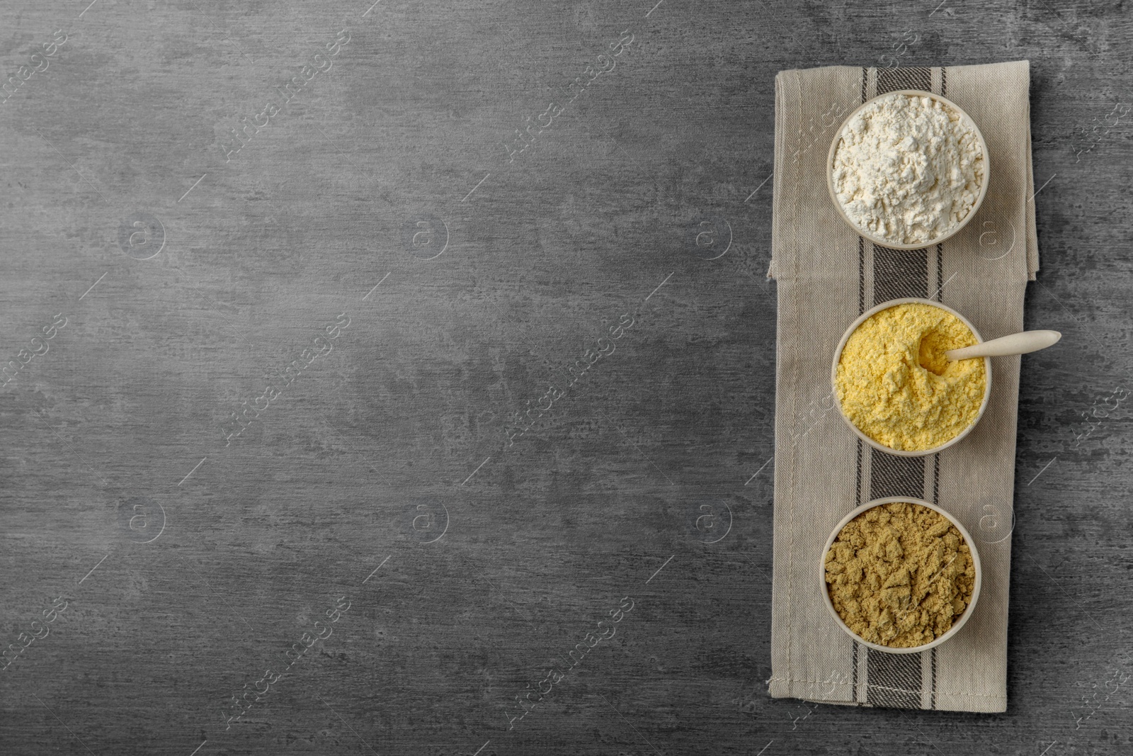 Photo of Bowls with different types of flour on gray background