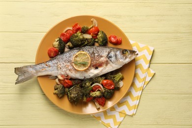 Photo of Delicious baked fish and vegetables on yellow wooden table, top view