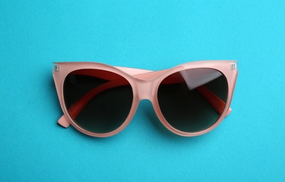 Stylish sunglasses on blue background. Fashionable accessory