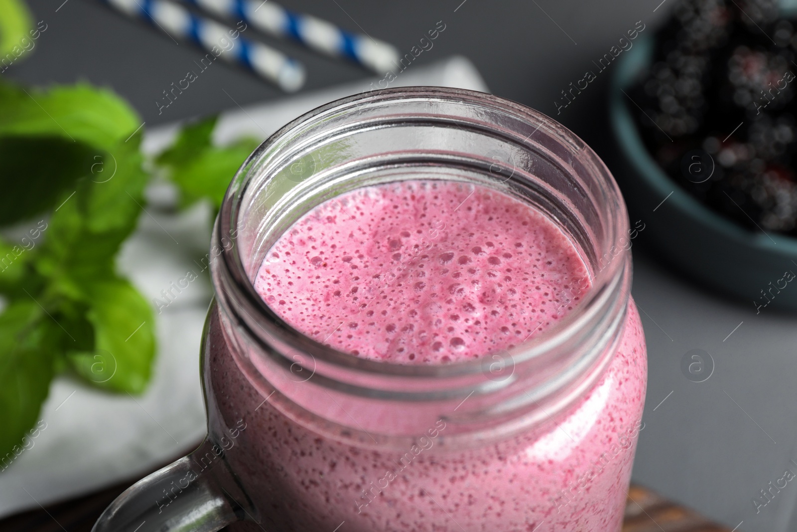Photo of Mason jar of blackberry smoothie on grey table, closeup