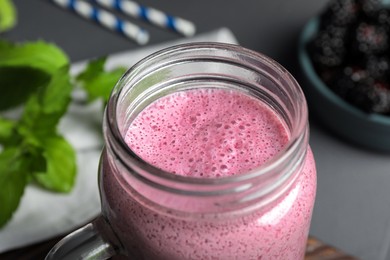 Mason jar of blackberry smoothie on grey table, closeup