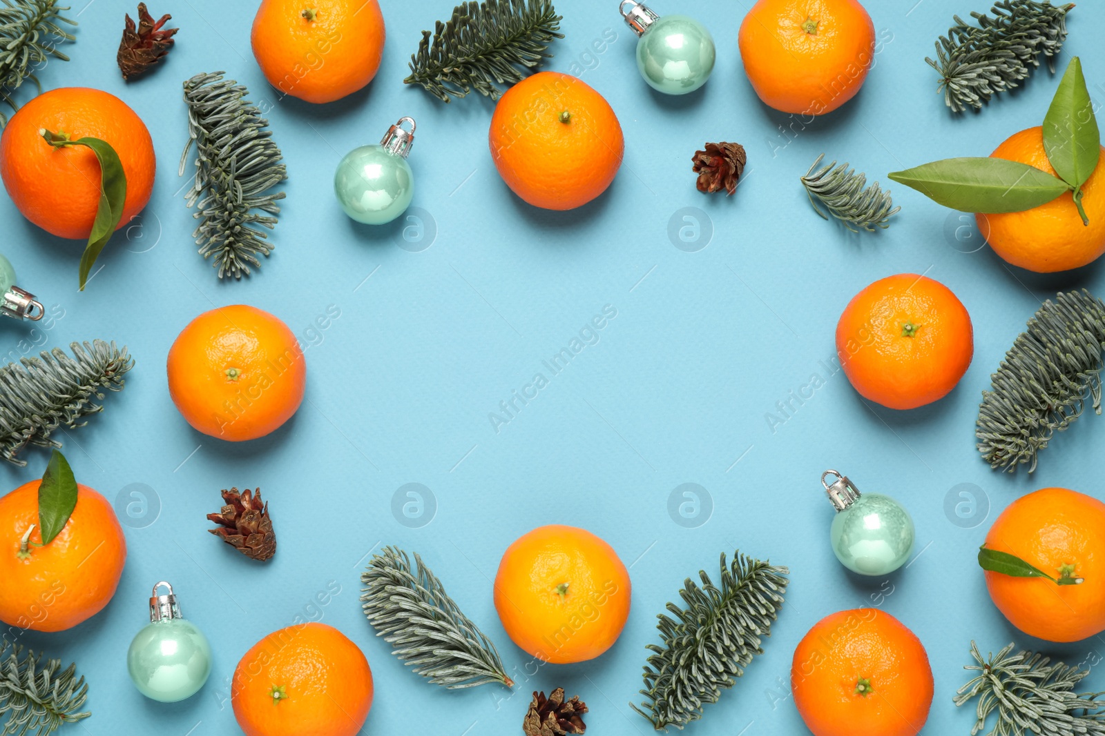 Photo of Frame made of Christmas balls and tangerines on light blue background, flat lay. Space for text