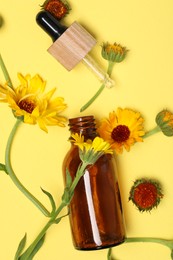 Photo of Bottle and pipette with essential oil near beautiful calendula flowers on yellow background, flat lay