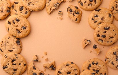 Photo of Frame made of many delicious chocolate chip cookies on beige background, flat lay. Space for text