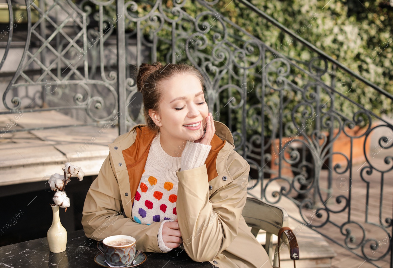 Photo of Young woman enjoying tasty coffee at table outdoors