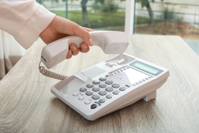 Photo of Woman using telephone at table indoors, closeup