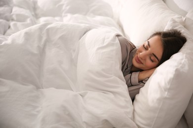 Photo of Beautiful young woman wrapped with soft blanket sleeping in bed at home