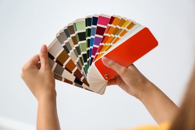 Female interior designer with color palette samples on light background, closeup